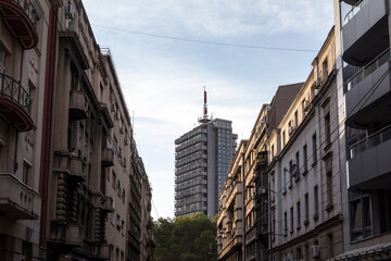 Fototapeta na wymiar Old residential buildings made of concrete and a 70s high rise steel skyscraper in the city center of Belgrade, the capital city of Serbia, during a sunny afternoon