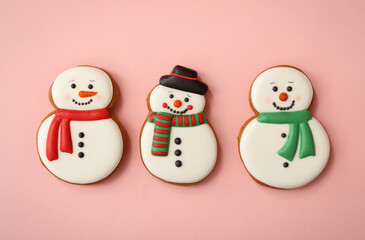 Christmas snowman shaped gingerbread cookies on pink background, flat lay
