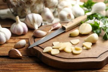 Fototapeta na wymiar Fresh whole and cut garlic on wooden table. Organic product