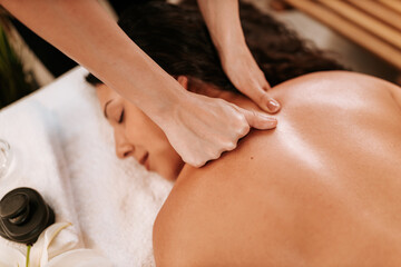 Beautiful young woman in the massage salon with brown curly hair and healthy skin. Masseur and patient concept.