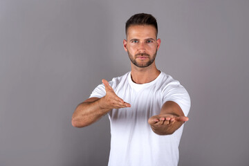 A young man in a white tshirt showing something with his palms