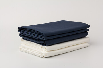 Stack of clean white and blue bed sheets on white  background, closeup.