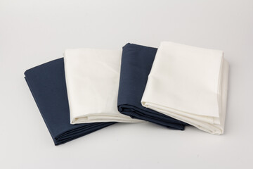 Stack of clean white and blue bed sheets on white  background, closeup.