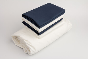 Stack of clean white and blue bed sheets on white  background, closeup.