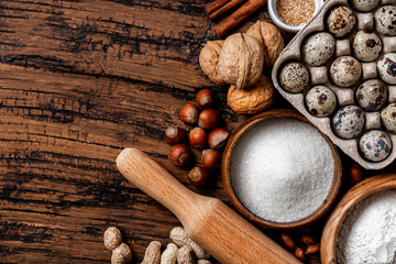 Ingredients for making a sweet pie or cookies with nuts on a old wooden table top view. Free space for text. Various nuts, flour, sugar, eggs and cinnamon flat lay. Food background. Copy space.
