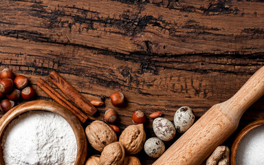 Ingredients for making a sweet pie or cookies with nuts on a old wooden table top view. Free space for text. Various nuts, flour, sugar, eggs and cinnamon flat lay. Food background. Copy space.