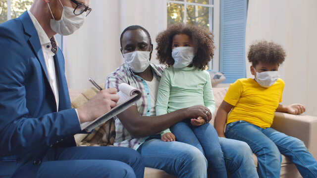 Insurance Agent In Mask Consulting Smiling Young African Man With Kids At Home.