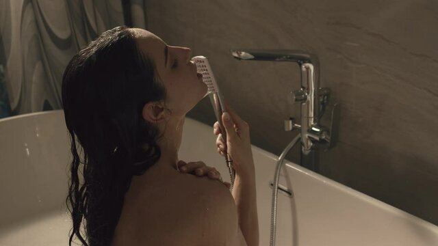 Naked girl taking shower in bathroom. Slim woman enjoying water treatments home