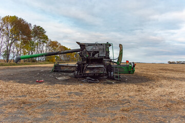 Aerial Back View of Burnt Combine Harvester on Grain Field in Rural North Dakota, taken at Daytime with Cloudy Sky.