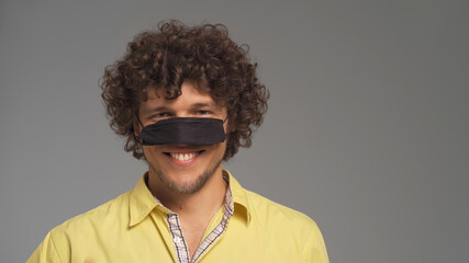 Obraz premium Funny man have fun wearing protective mask on his nose. Cut out on gray background. 