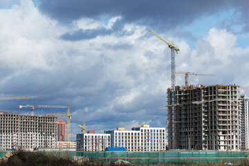 Construction of modern multi-storey buildings. New development of a residential area. House frames, construction cranes and building materials at the construction site.