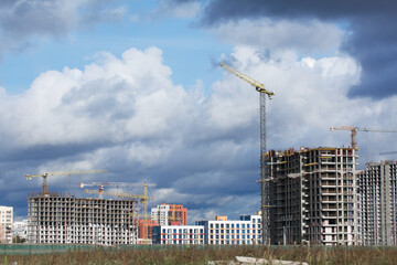 Construction of modern multi-storey buildings. New development of a residential area. House frames, construction cranes and building materials at the construction site.