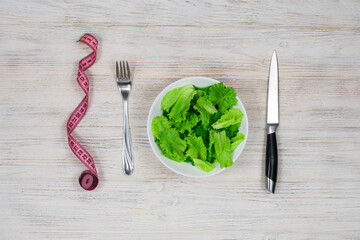 Green salad in a white bowl on a wooden table.