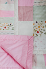 Pink patchwork blanket top view.  Cozy baby girl cot with blanket. Bedding and textile for children nursery. Nap and sleep time 