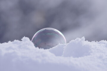 Seifenblasen im Sonnenlicht vor Schnee und Bergen