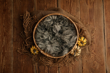 Prop digital background of newborn photography.  wooden basket with green fur and decorated with small pumpkins on a wooden background.