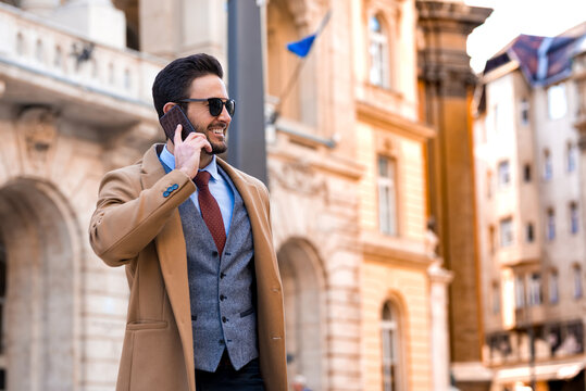 An elegant man standing on a square and talking on his phone