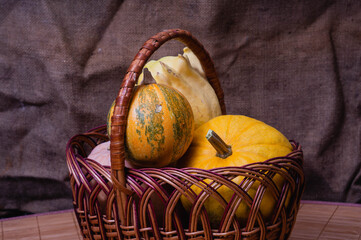 Basket full of small, cool looking pumpkins. Sackcloth background. Autumn mood