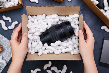 Female hands unpacking parcel with camera lens inside. Big sale in electronics store or online...