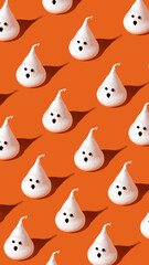 Creative pattern made with ghost meringue on orange background. Minimal Halloween concept. Greeting card, flat lay.