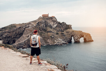 Young man with a hat in front of the Gaztelugatxe Island