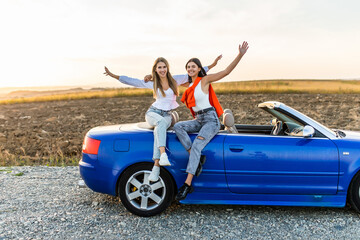 Two happy women friends taking selfie when road trip in convertible car.