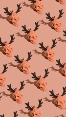 Halloween pattern made with orange skulls with elk antlers on pastel background. Heavy trendy shadows. Contemporary horror aesthetic. Flat lay.