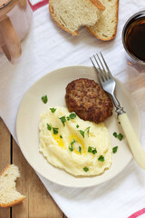 Cutlet, mashed potatoes with butter and parsley and tea on a wooden table.
