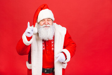 Santa Claus standing isolated on red background. Christmas and new year concept. Pointing finger.