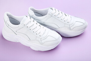 Pair of white shoes on purple background