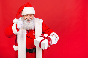 Photo of happy Santa Claus with present gift boxes lsolated over red background. Christmas and New Year concept.