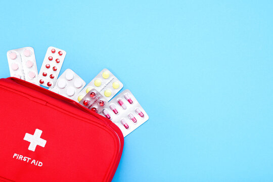 First aid kit with colorful pills on blue background