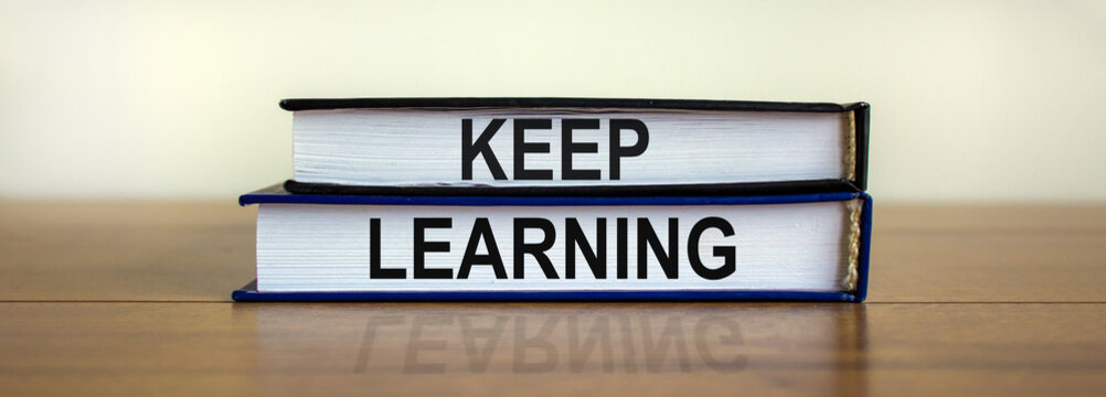 Books with text 'keep learning' on beautiful wooden table. White background. Business concept. Copy space.