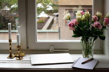 Ready for online dating with candles, fresh roses and laptop by the window