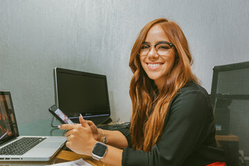 mujer joven mexicana trabajando hablando por telefono contenta divertida orgullosa