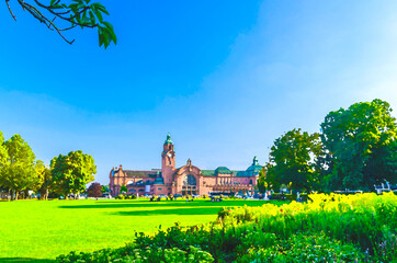 Watercolor drawing of Wiesbaden Hauptbahnhof central railway station Neo-baroque style building and Reisinger-Anlagen park with green trees and lawn in historical city centre, State of Hesse, Germany