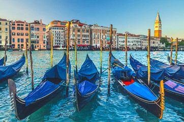 Fototapeta na wymiar Watercolor drawing of Gondolas moored in water of Grand Canal waterway in Venice. Baroque style colorful buildings along Canal Grande and bell tower Campanile di San Marco. Typical Venice cityscape