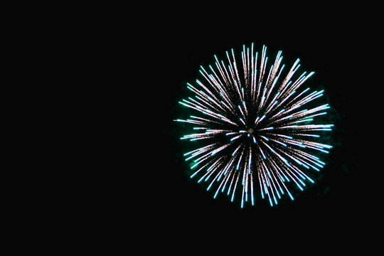 fireworks glow and turquoise sparkles in the night sky.
