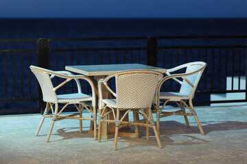 Empty table and chairs at beach restaurant near ocean. Evening, blue hour..