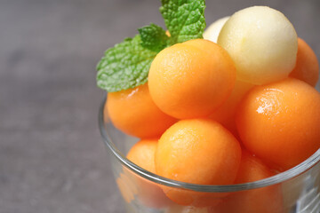 Melon balls and mint in glass on grey table, closeup. Space for text