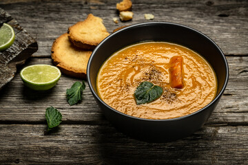 Carrot cream-soup. Vegetarian vegetables soup with baked peppers, carrots and cheese, lime juice and ginger, served with nuts and fresh mint, Close up