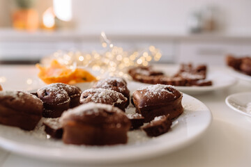 Fresh homemade chocolate chip cookies in coconut and sugar crumbs on a white plate and garland lights in the background.