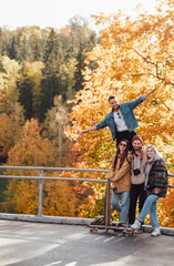 Fototapeta premium Four joyful friends one of them showing he is flying having a good time spending their holidays together in auturm park in daytime.