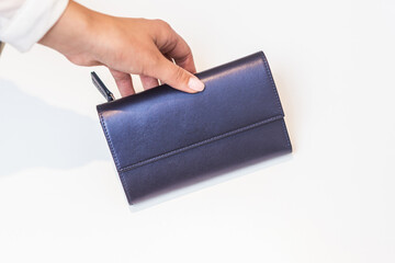 Girl holds blue purse on white table