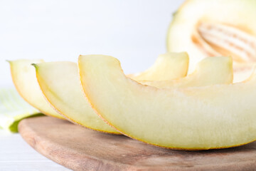 Pieces of delicious honeydew melon on wooden board, closeup