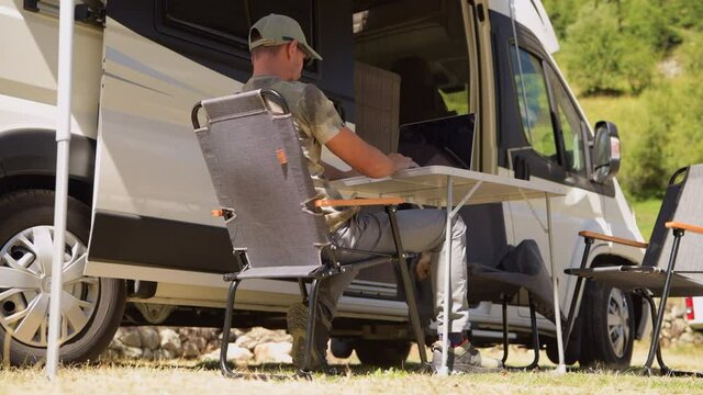 Caucasian Men in His 40s Working Remotely From Camping Pitch While on RV Recreational Vehicle Road Trip