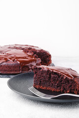 Chocolate cake in a black plate with a fork on a white background with copy space vertical