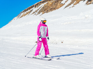 Fototapeta na wymiar A skier in a pink suit rides a straight track on a clear winter day