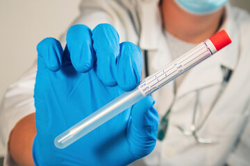 Doctor holding coronavirus swab test sample in a vial with gloves and face mask at laboratory. Close up