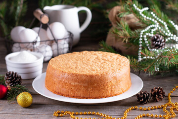 Homemade round sponge cake or chiffon cake on white plate so soft and delicious with ingredients: eggs, flour, milk on wood table. Basis for making holiday cakes and desserts. 